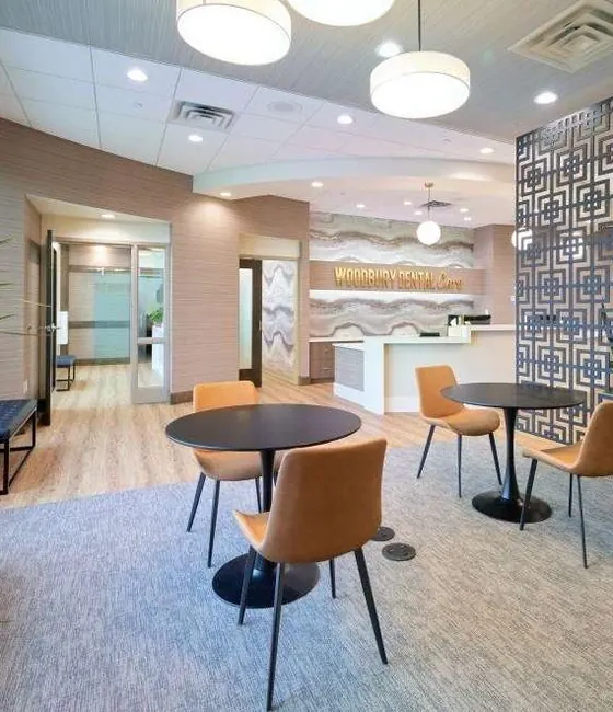 Café tables and leather chairs by the coffee bar in the Woodbury Dental Care lounge.