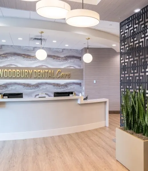 The reception desk at Woodbury Dental Care, with the practice's name in gold lettering on a marble wall.