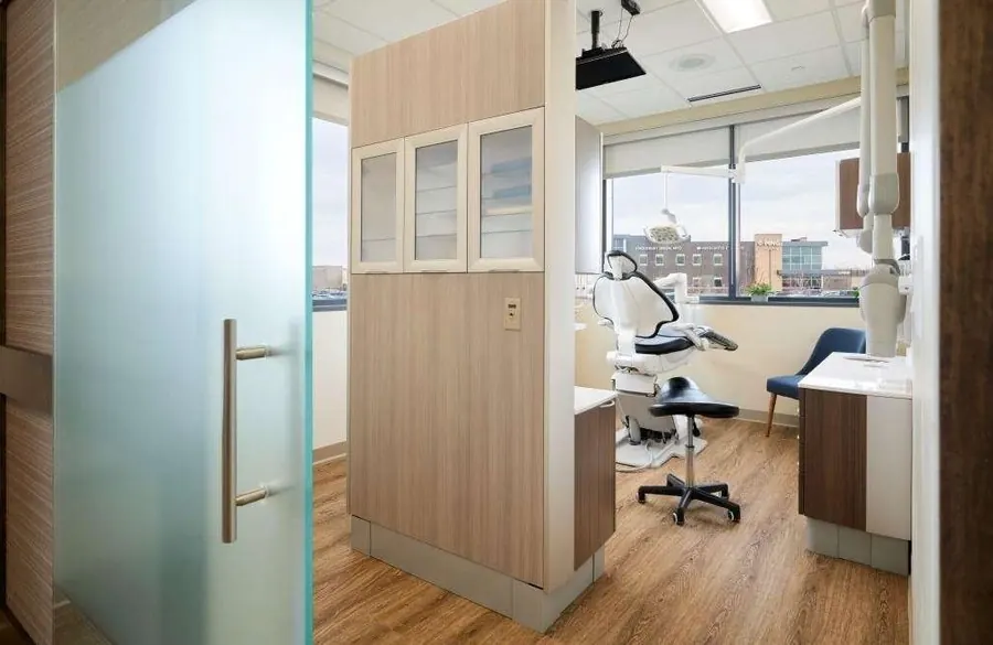 A treatment room at Woodbury Dental Care, seen through its frosted glass door, with a window onto Woodbury.
